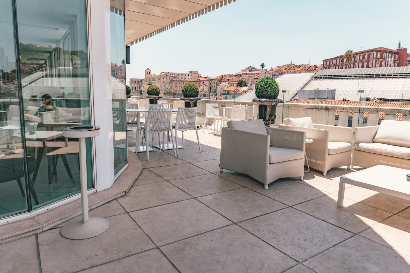 Terrazza sul tetto con sedute in vimini bianco e vista sulla città.