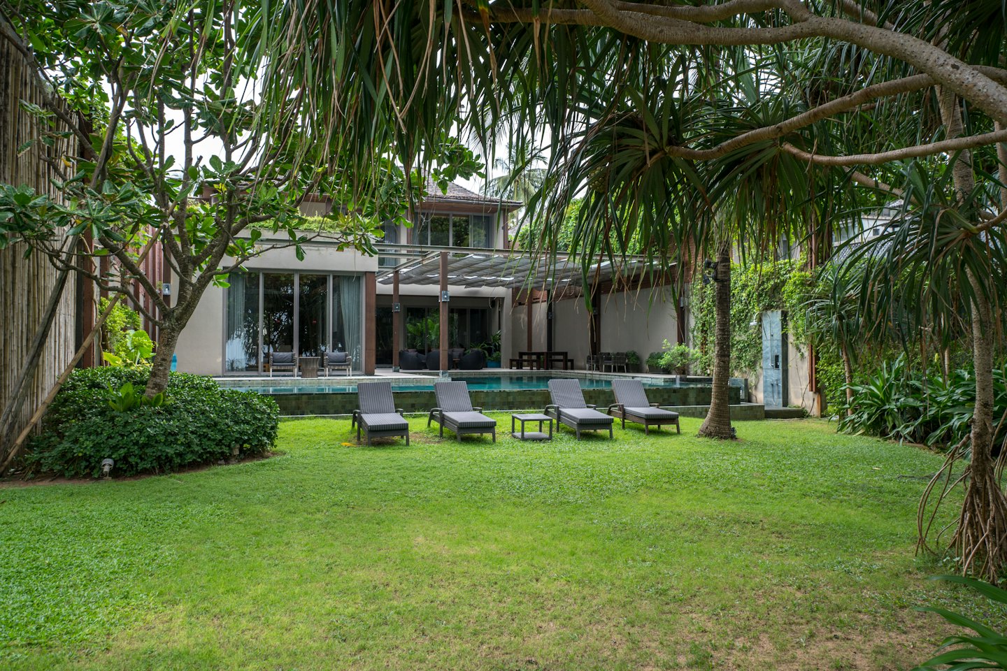 Villa moderna con piscina e sedie a sdraio sul prato.